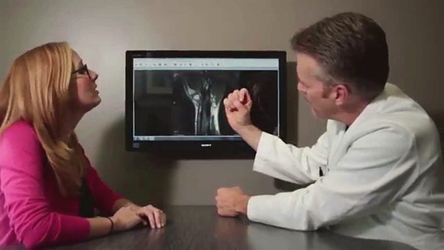Dr. John Knight talking with a patient in front of a wrist scan.
