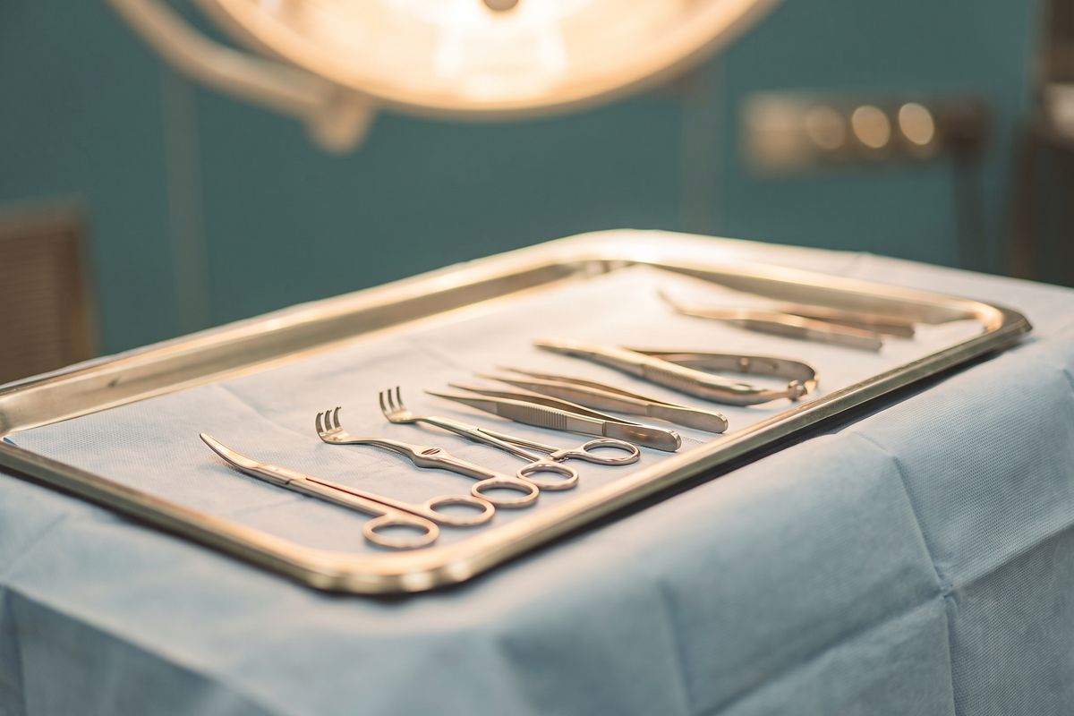 A tray of hand surgery instruments laid out on a blue drape under the operating light.