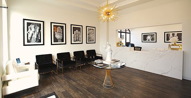 The waiting room at our Southlake office, with black leather seating, a marble reception counter and framed photographs of hands on the walls.