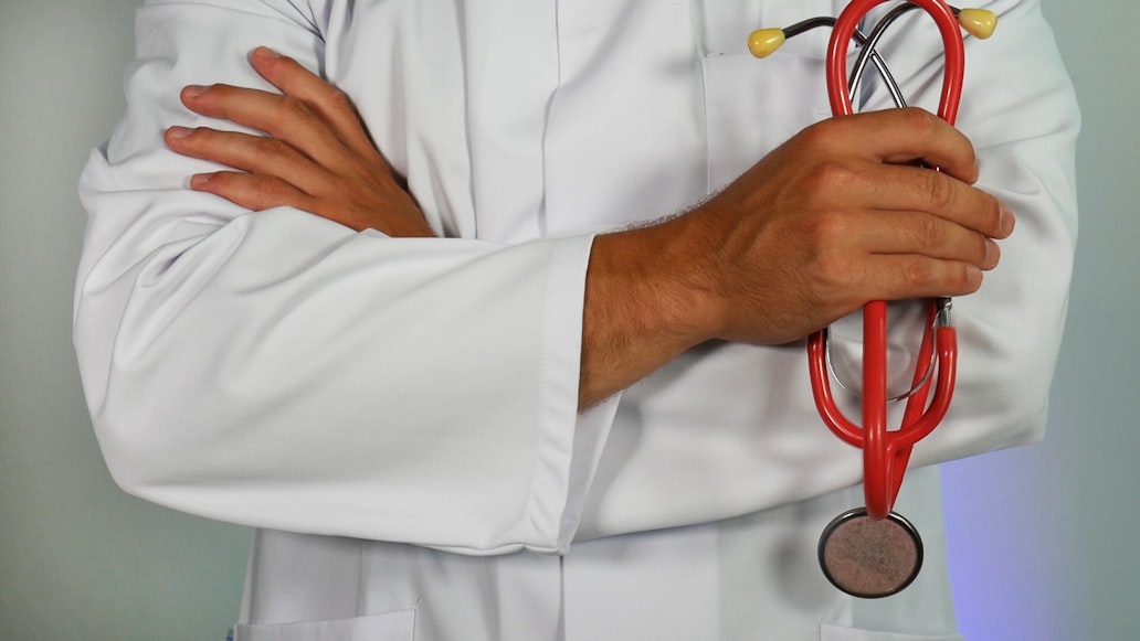 Doctor/nurse with arms folded holding a stethoscope.
