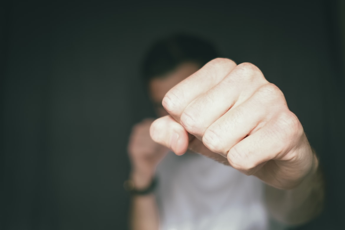 A closed fist held towards the camera, the person behind it out of focus.