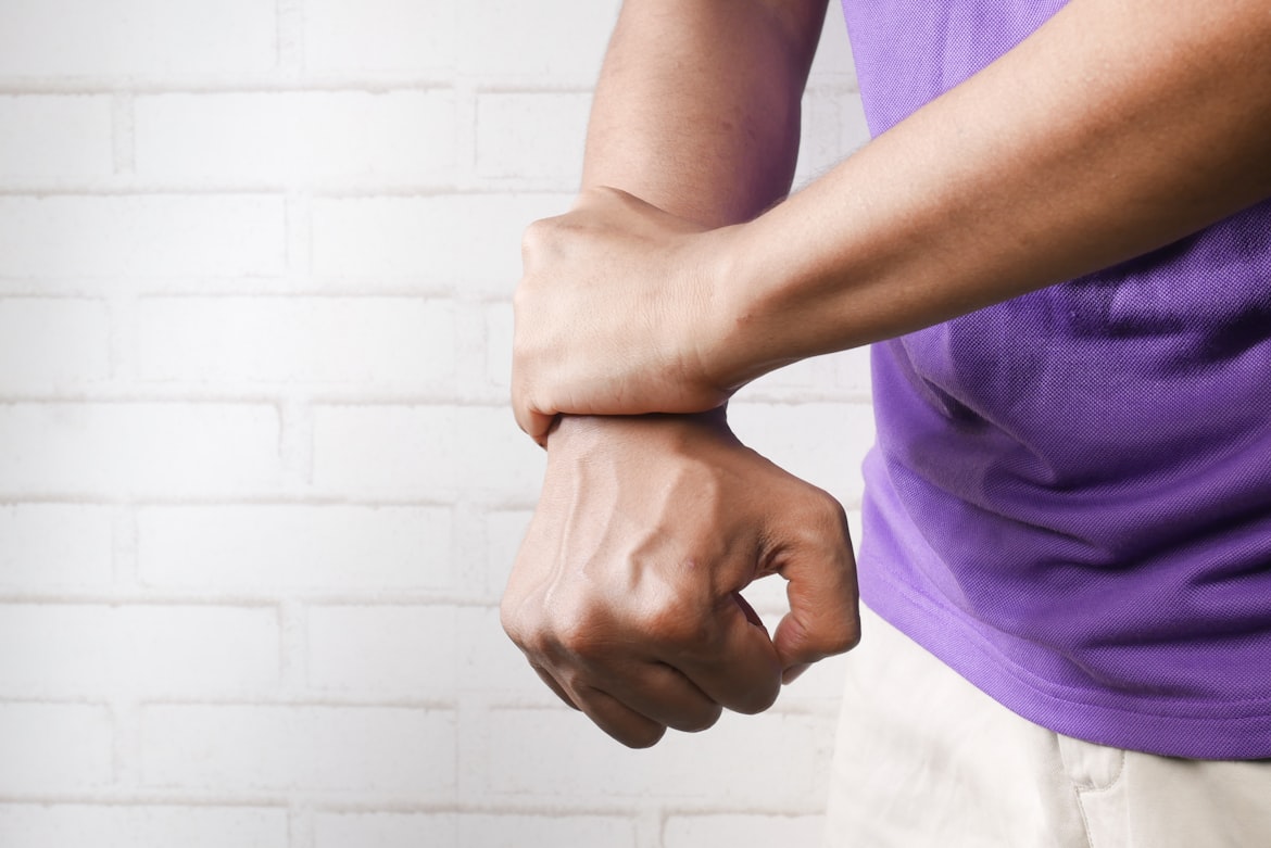 Person holding their wrist with the other hand.