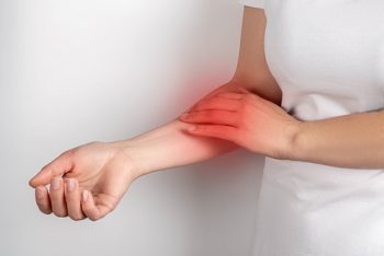 Pain in the arm, a woman touches a sore arm