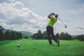 man in a green shirt teeing off