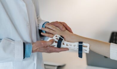 Doctor fastening a wrist brace onto a patients arm.